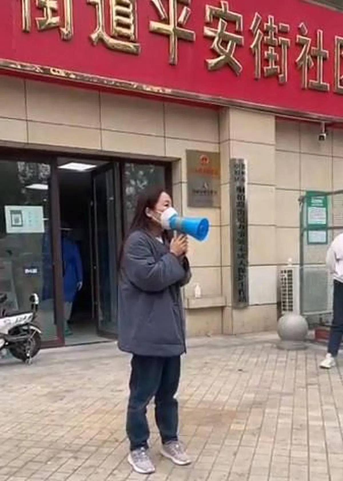 刘红英站在平安街社区前拿着喇叭喊冤，称不觉得自己做错了什么。（视频截图）