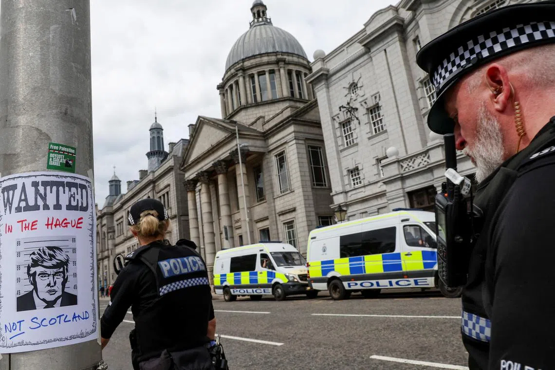 英国苏格兰阿伯丁警方出动大批警力，到示威现场维持秩序。其中一个柱子被示威者贴上通缉特朗普的告示。（路透社）