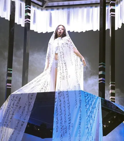 Jennie以白色露肚装搭配超短热裤，头上披着写满汉字和韩文的白纱登场。（取自MMA X）