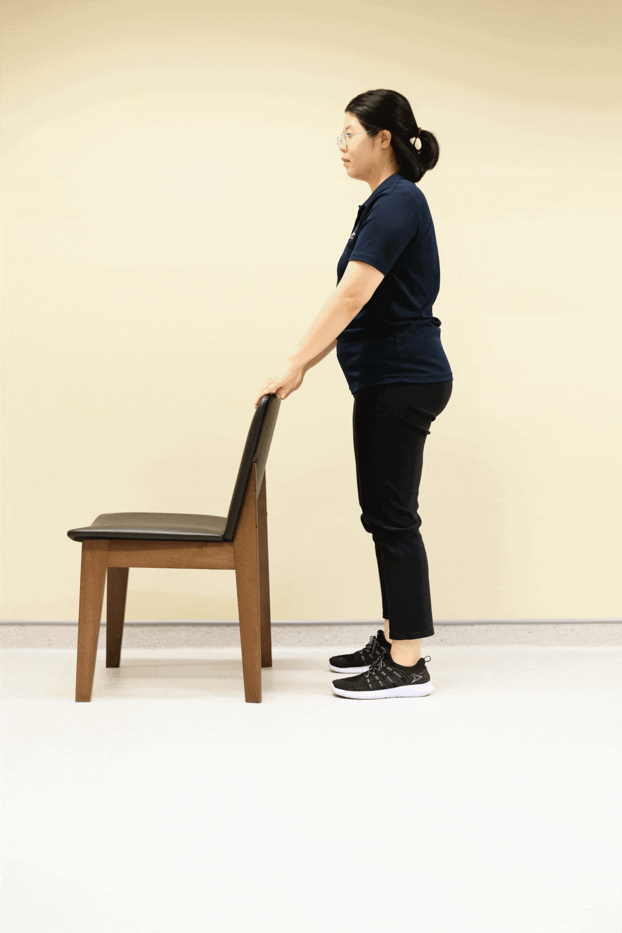 深蹲是每天都应做的运动，刚开始练习时不妨扶着椅背。（龙国雄摄）