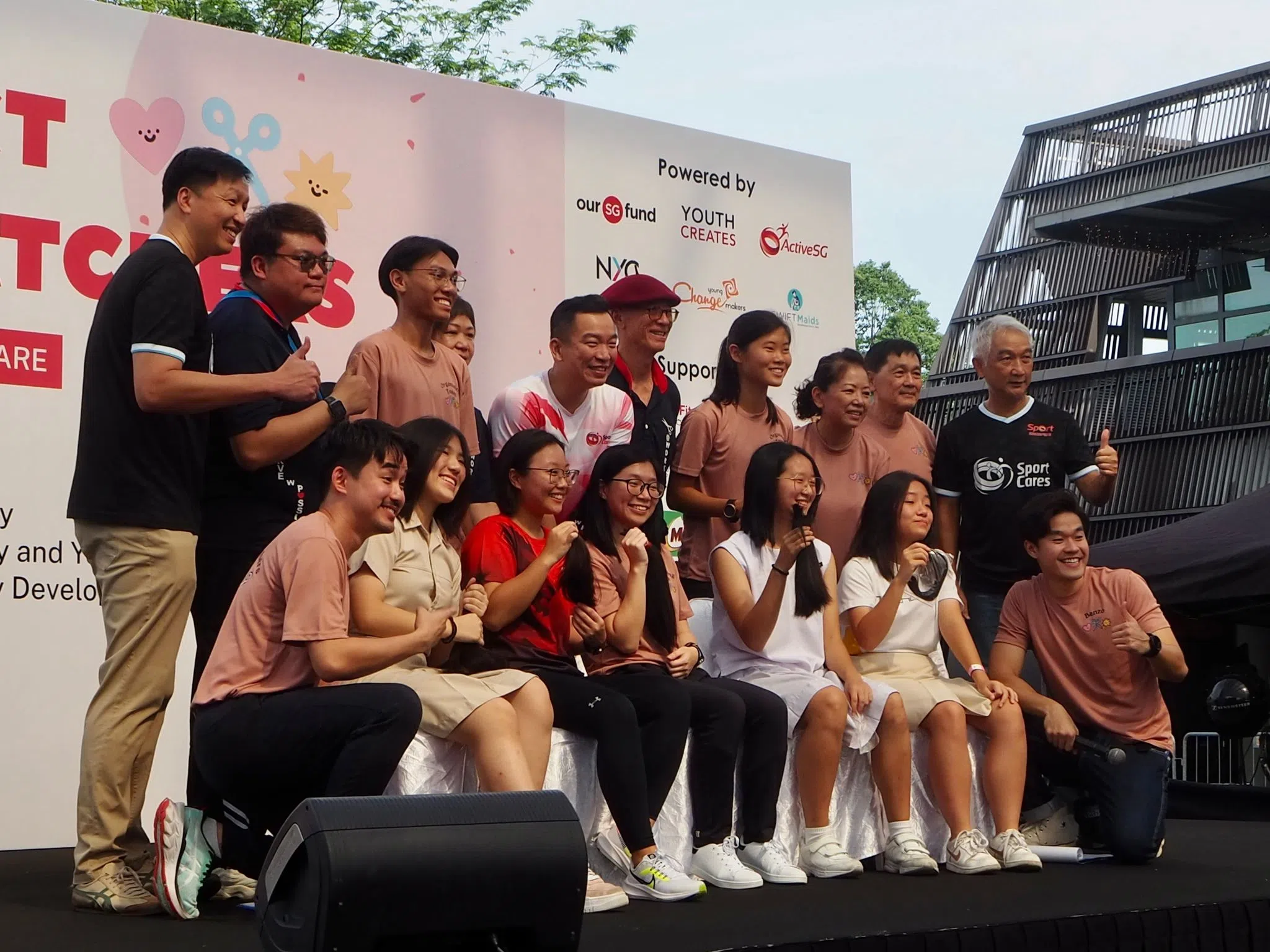 捐发者手持剪下的头发，和文化、社区及青年部兼社会及家庭发展部高级政务次长蔡瑞隆（后排中间站立者）及义工合影留念。（唐诗音摄）