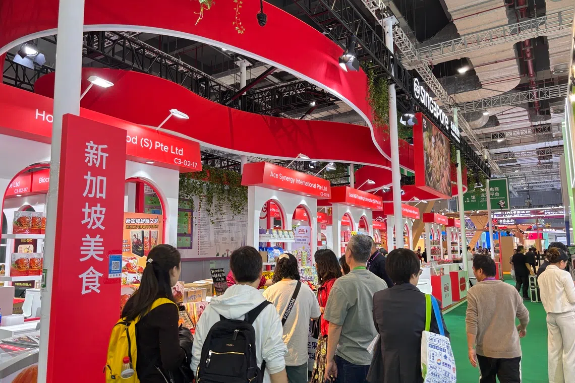 22家新加坡农食产品企业参加今年进博会，图为看展中国民众在一家美食摊位前驻足品尝。（黎康摄）