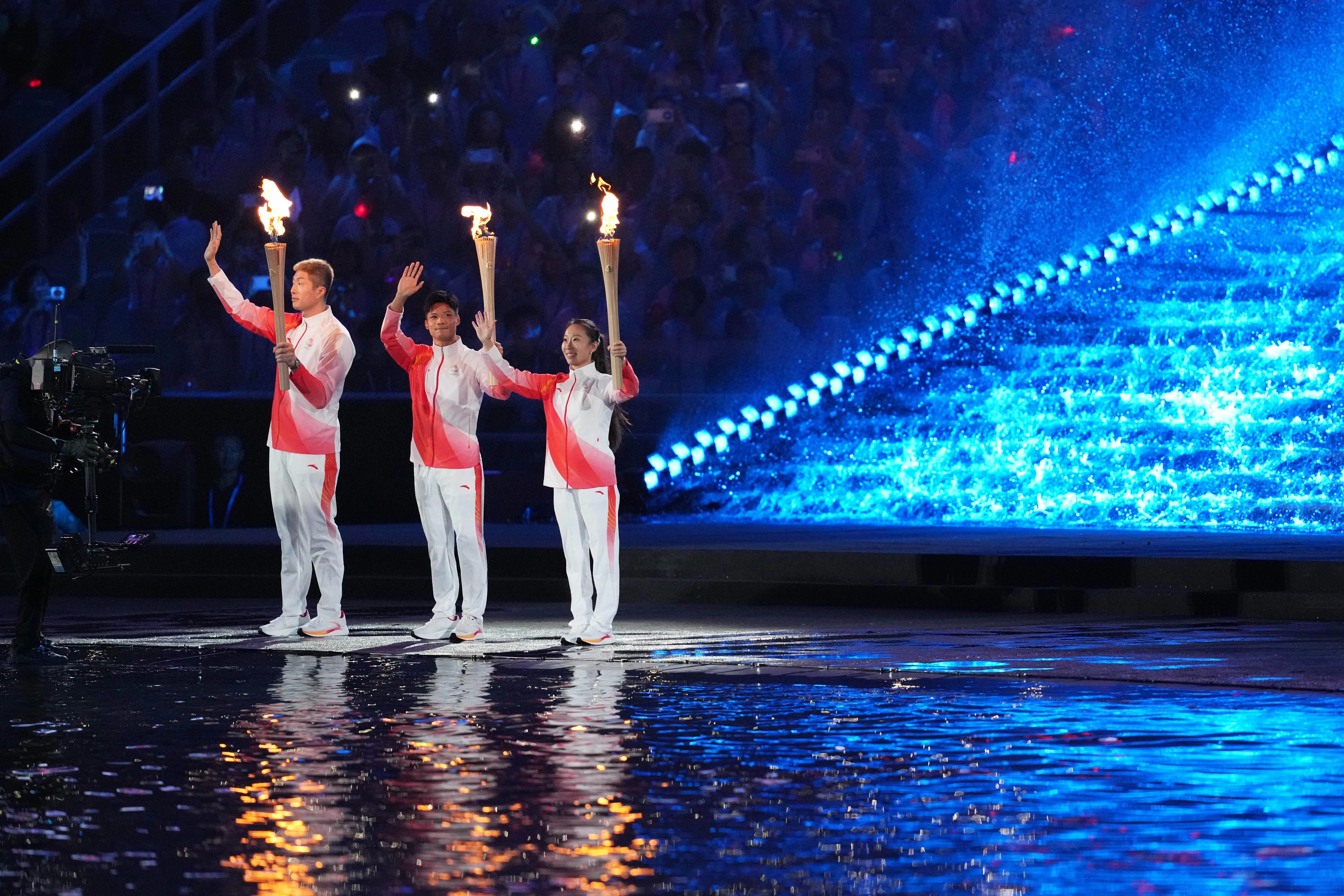 张家朗（左一）、苏炳添（左二）和李祎点燃主火炬。（新华社）