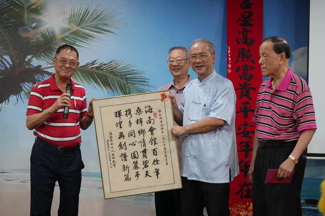 海南会馆会长潘家海（右二）从海南籍南大毕业生王白安（左一）手中接过他的书法作品。右一为海南籍南大毕业生代表王新民，左二为琼州天后宫主席王振胡。（谢智扬摄）