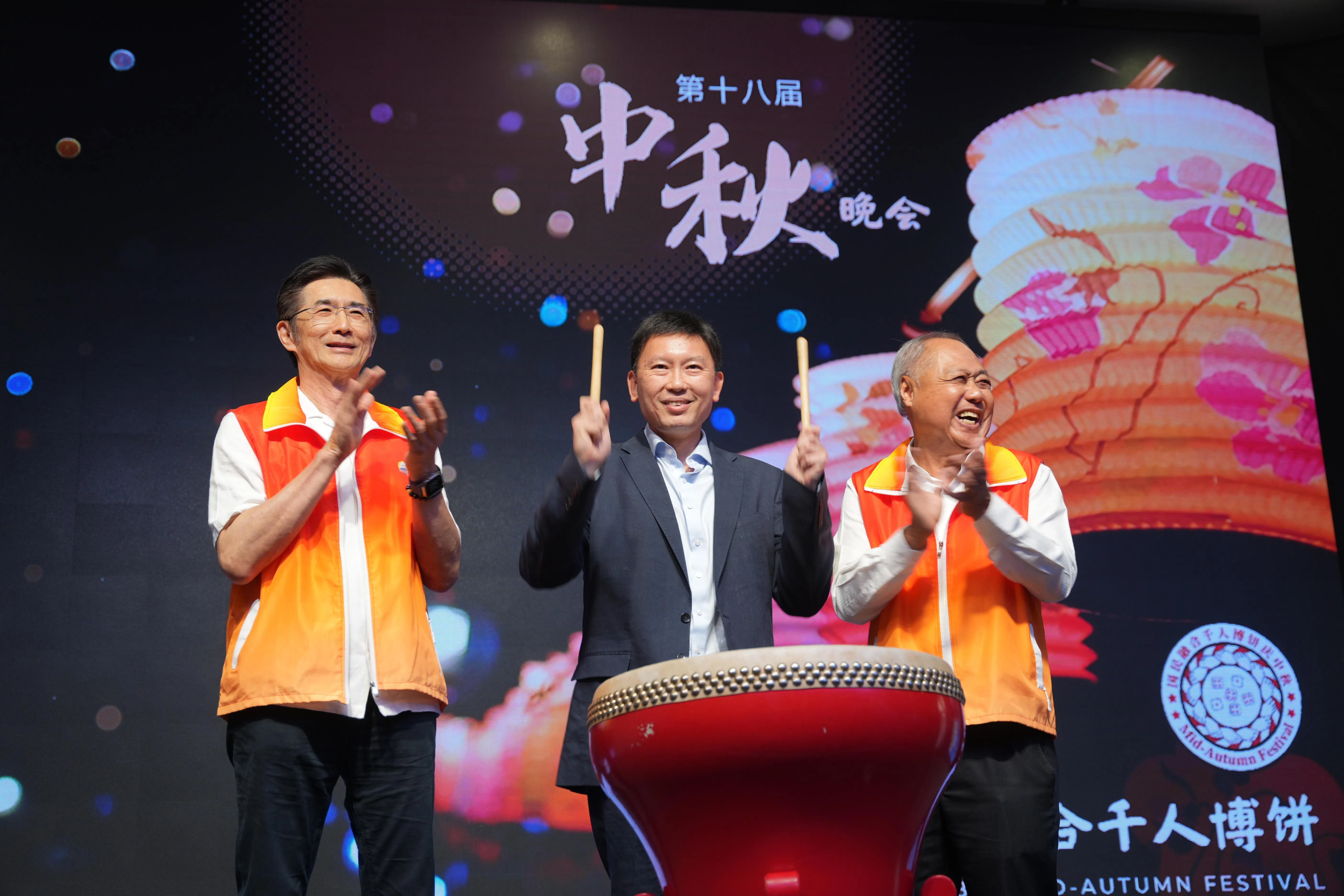 国家发展部长徐芳达（中）在台上击鼓，示意博饼游戏开始。博饼游戏是福建厦门等地的民俗活动，也是庆中秋时爱玩的游戏。右为厦门公会会长汪家裕，左为晚宴工委会主席吴斯仁。（谢智扬摄）