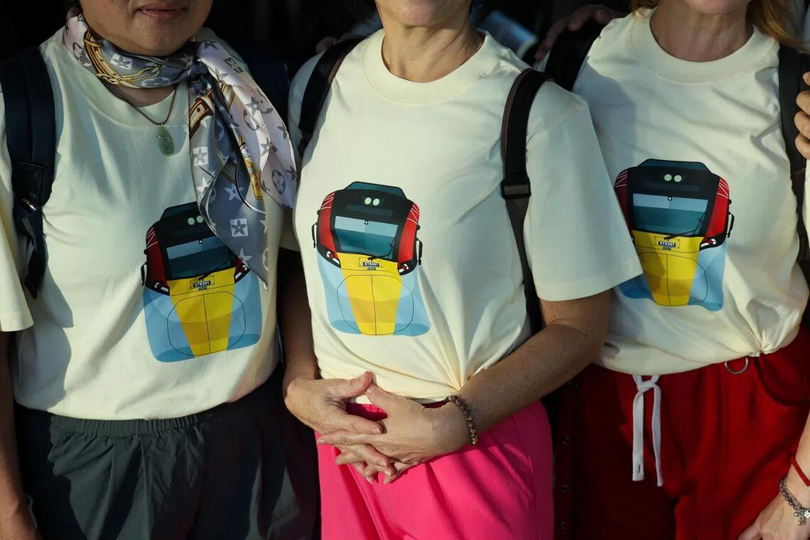 一群因健身舞而结识的好友穿上电动列车首发当天发售的纪念T恤，在新山中央车站上车。（张俊杰摄）