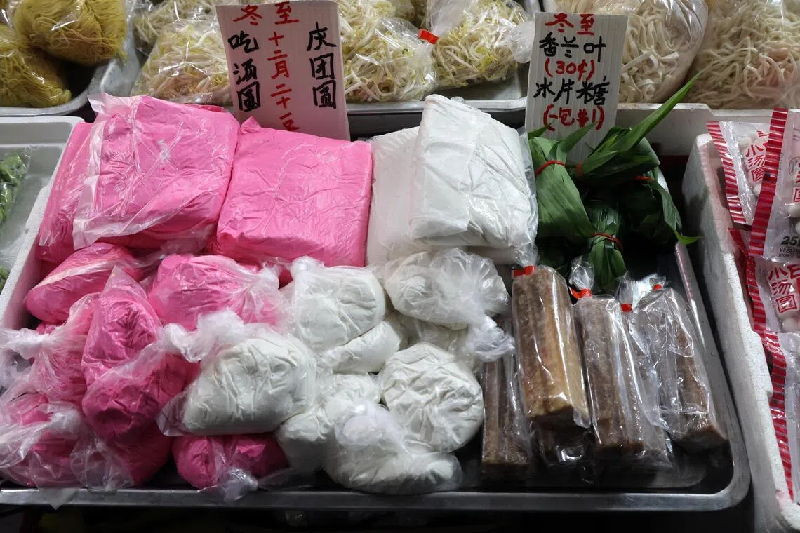 沈亚玉将糯米粉搓成红白两色的糯米团出售，并在摊位旁同步售卖香兰叶和椰糖。多年来，她始终维持每公斤6元的售价，并未涨价。（邝启聪摄）