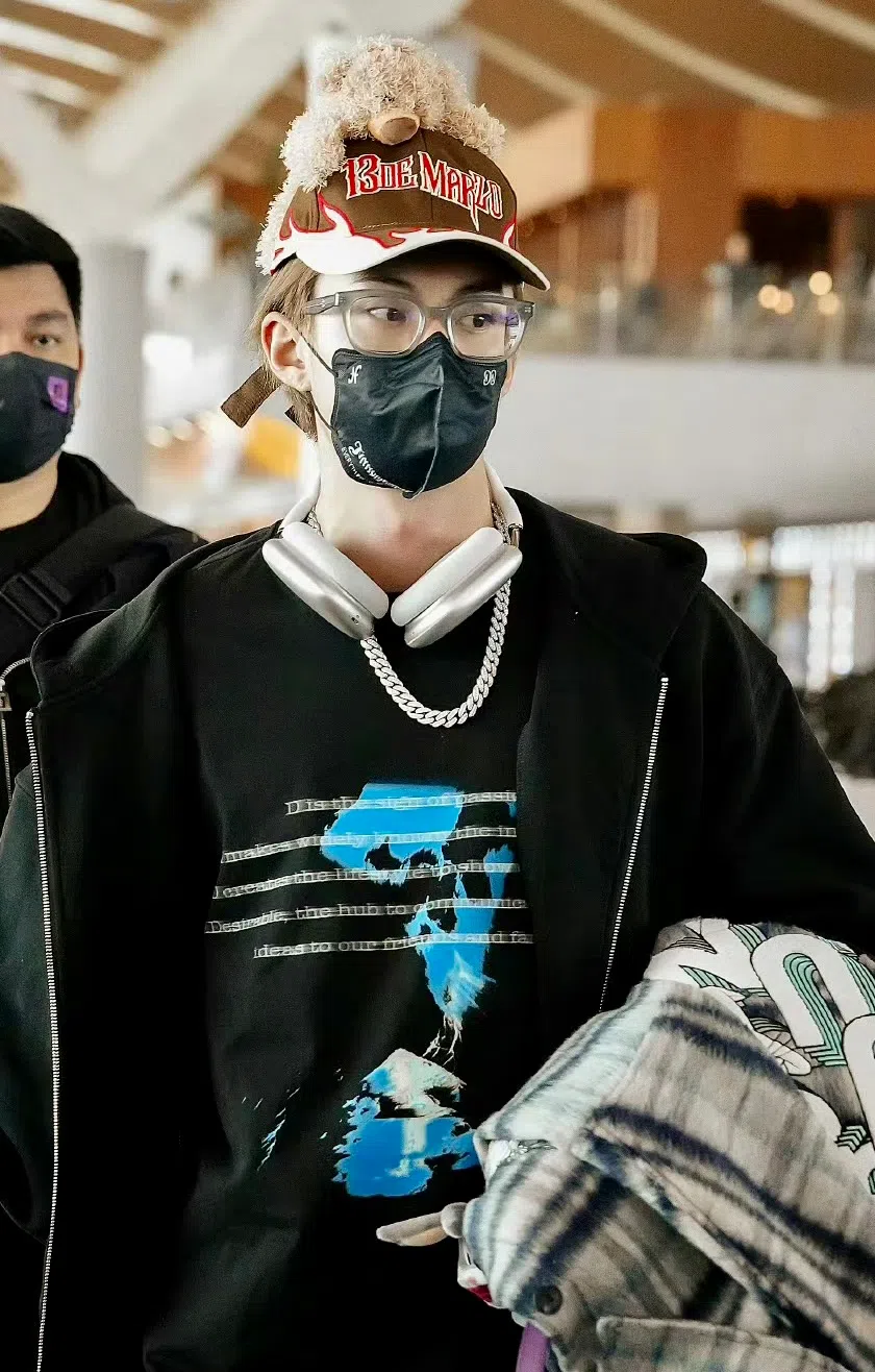 王鹤棣被直击现身上海浦东机场时，除了眼镜、耳机挂脖子，还戴着一顶小熊玩偶的鸭舌帽，造型格外吸睛。（取自微博、小红书）