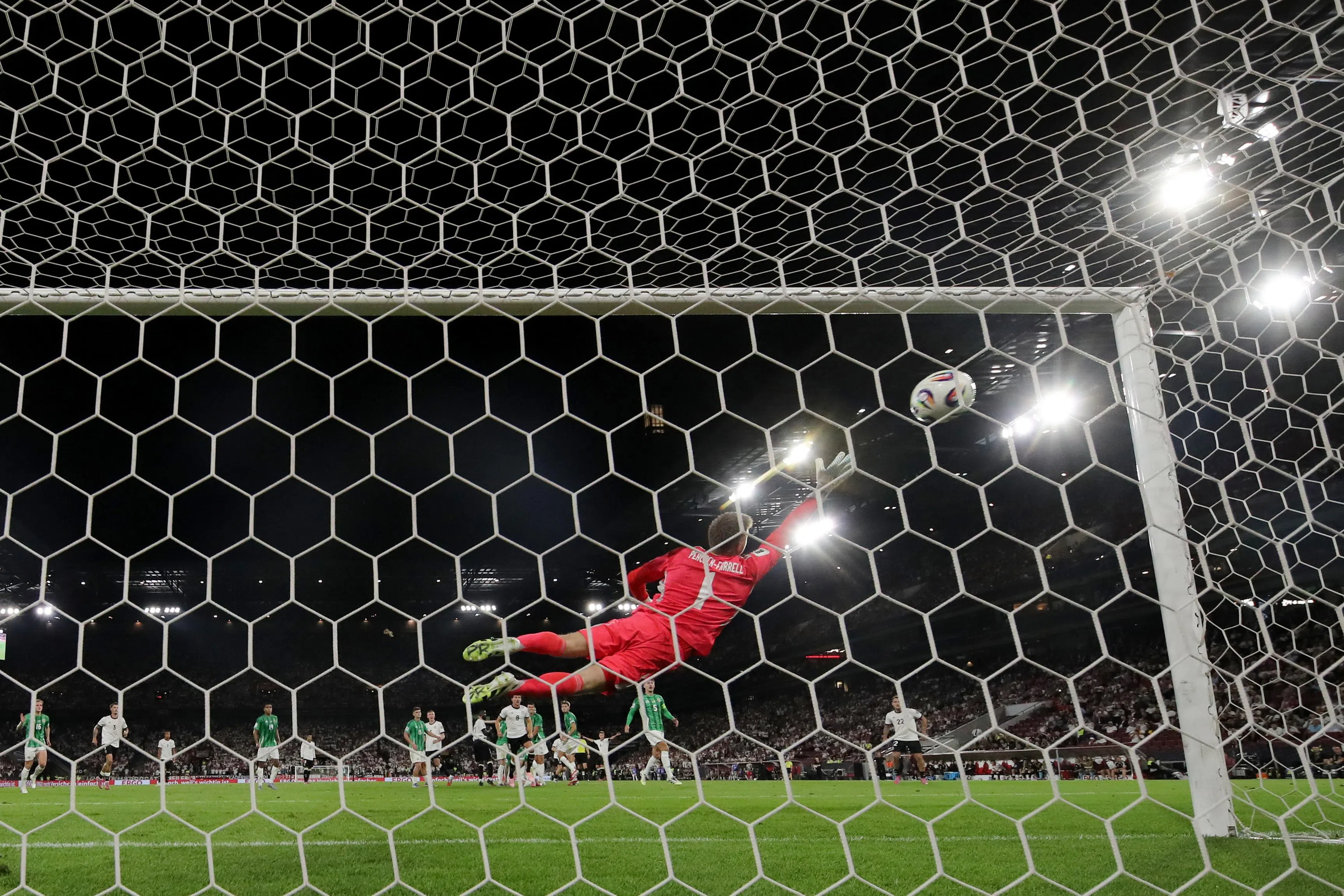 德国中场维尔茨主罚的自由球钻入球门死角，北爱尔兰门将皮科克—法雷尔（红衣）尽力扑救但仍无法阻止进球。（路透社）
