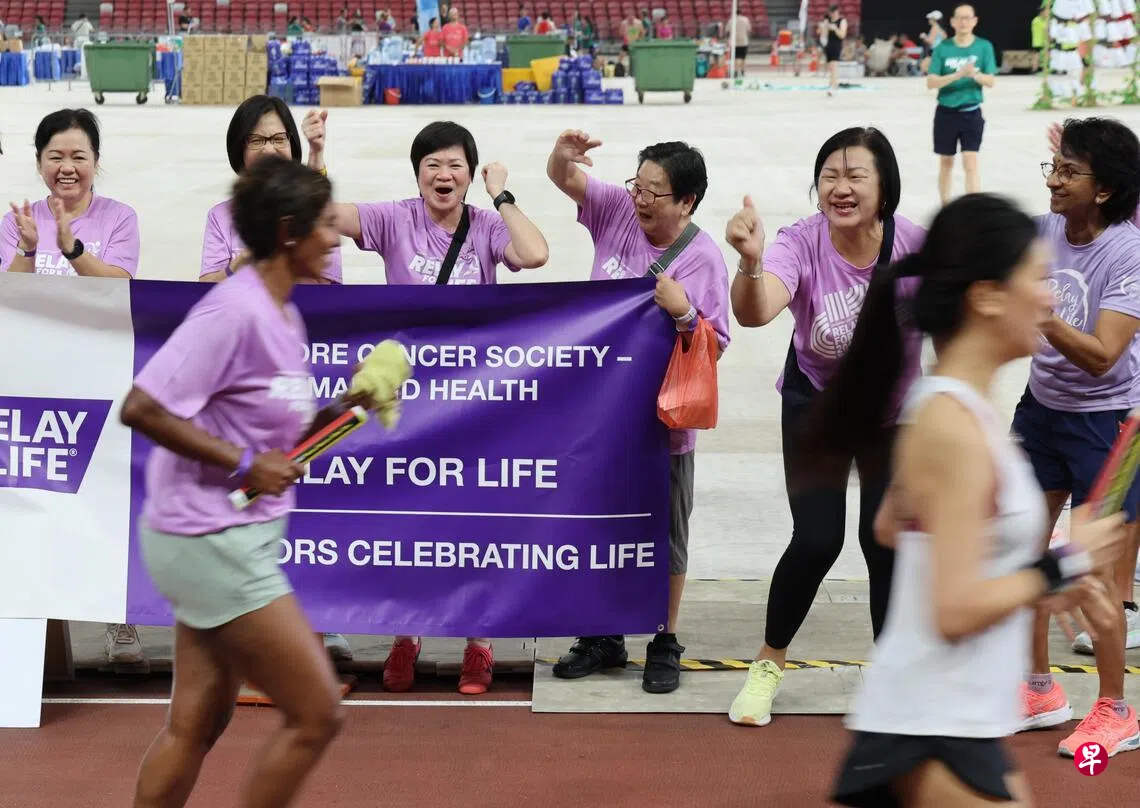 Image 14: 癌症康复者涂优金（左三欢呼者）星期天（3月15日）在国家体育场，和同伴们一起，给参加“为生命接力”的参与者助威呐喊。 （梁麒麟摄）