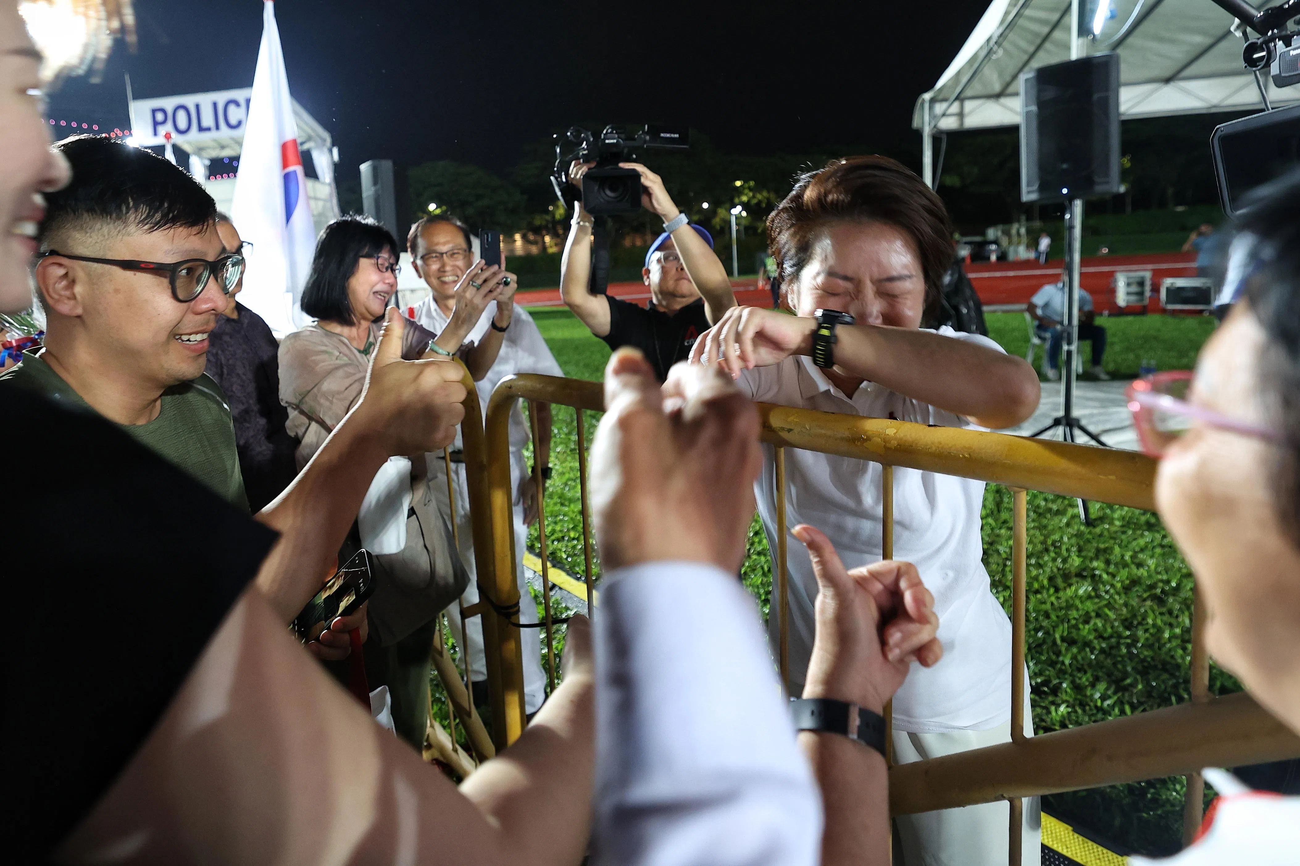 人民行动党蒙巴登区候选人吴诗琪（右一）在群众大会现场发言后，看到居民对她的热烈支持，激动落泪。（郑一鸣摄）