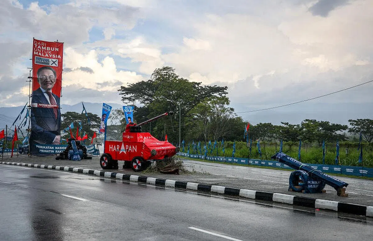 希盟及公正党主席安华的巨型海报设置在路旁后，国盟竞选团队立即摆出数个“坦克车”对准海报发起攻势。希盟也不甘示弱，后来也祭出更大的“坦克车”对峙，你来我往，创意十足。图摄于11月16日。（叶振忠摄）