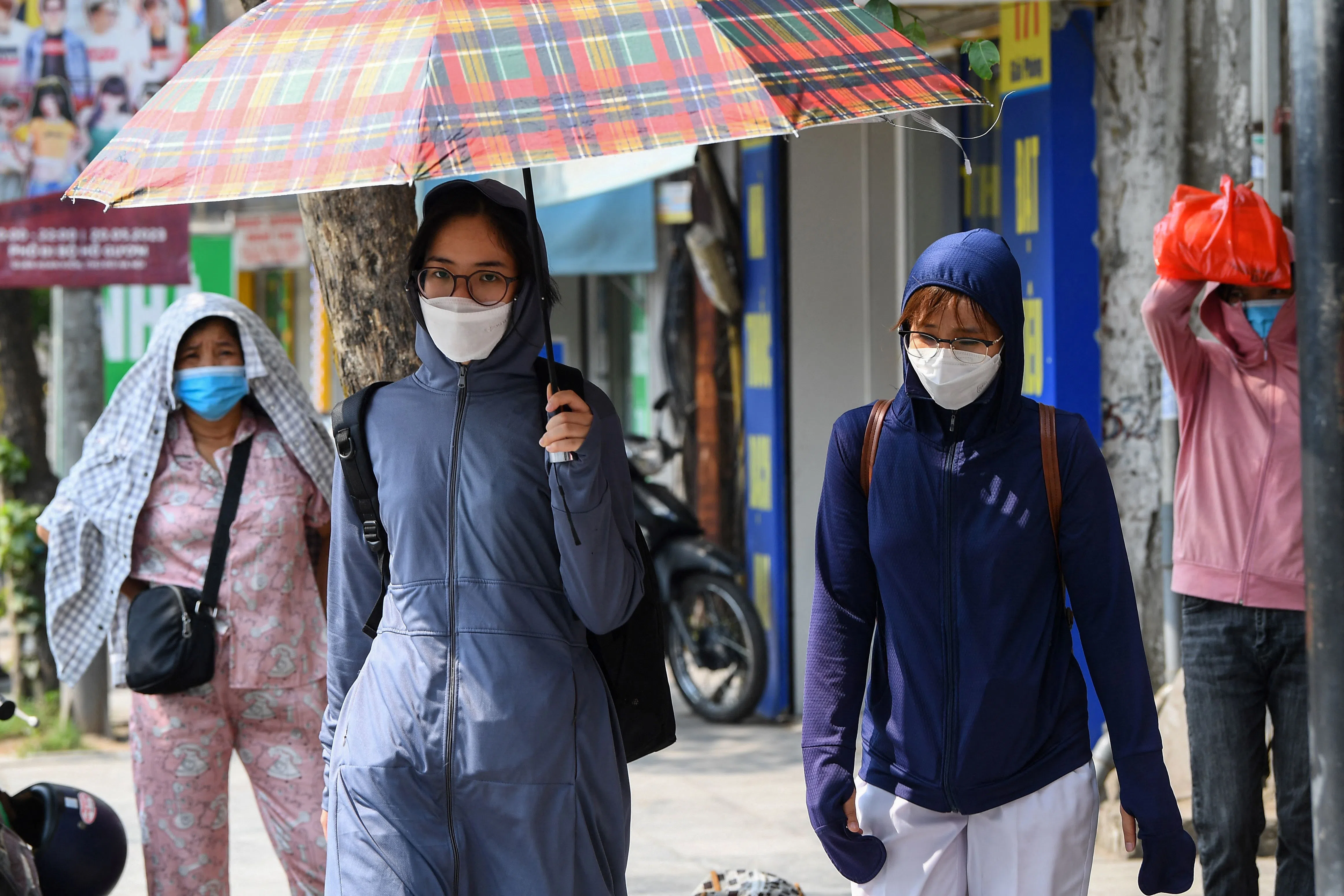 越南出现高温天气，在首都河内，民众纷纷撑伞或遮住头部避暑。（法新社）