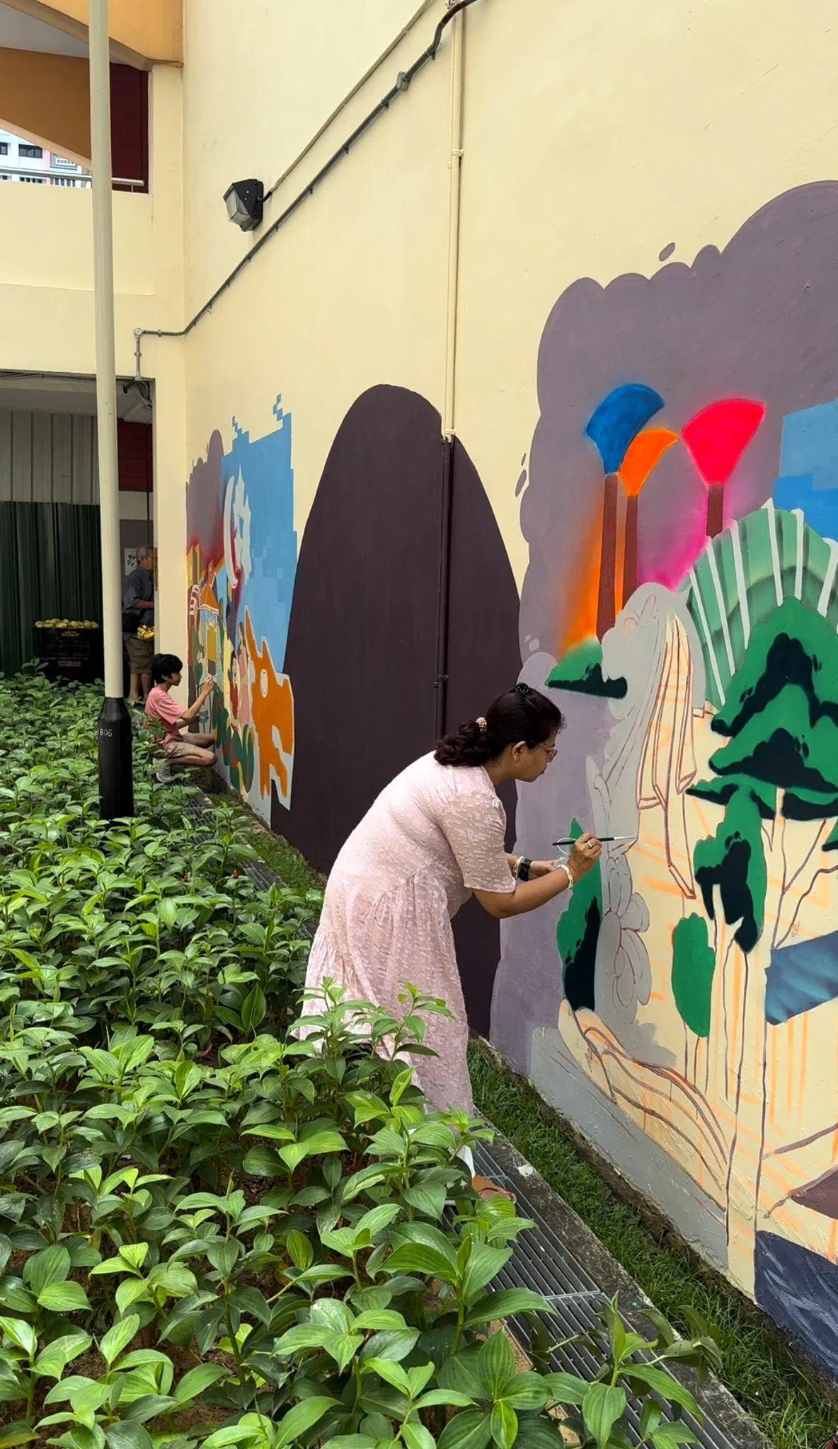 惹兰勿刹居民和社区义工，与南洋艺术学院学生携手创作霓虹主题壁画，融入新加坡地标与特色，为惹兰勿刹嘉年华倒数活动增添缤纷色彩，展现社区团结与创意。（甘榜格南选区办事处提供）