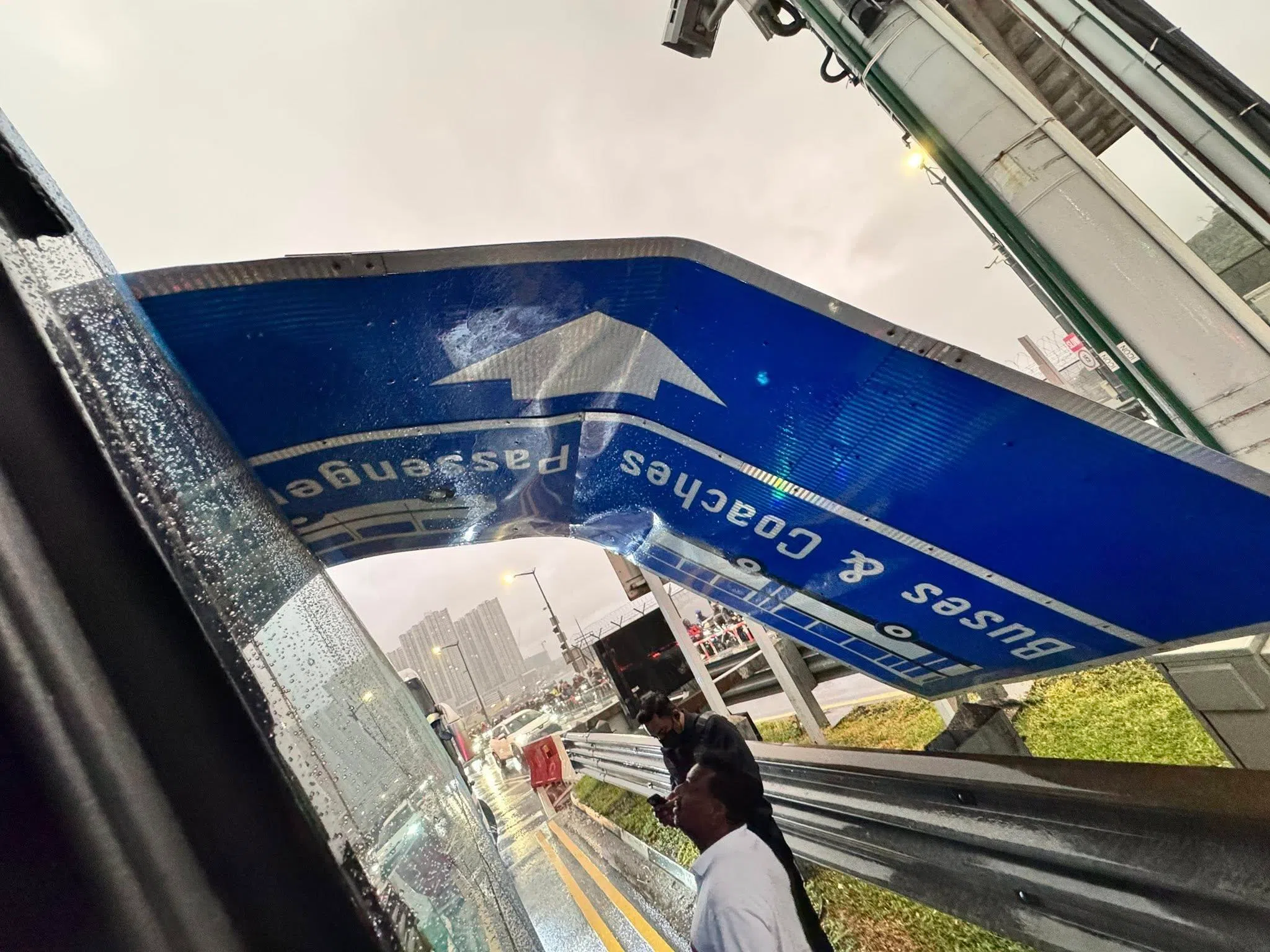 一块悬挂在车道上方的巨型蓝色路牌从高处落下，路牌因撞击而变得弯曲。（取自脸书）