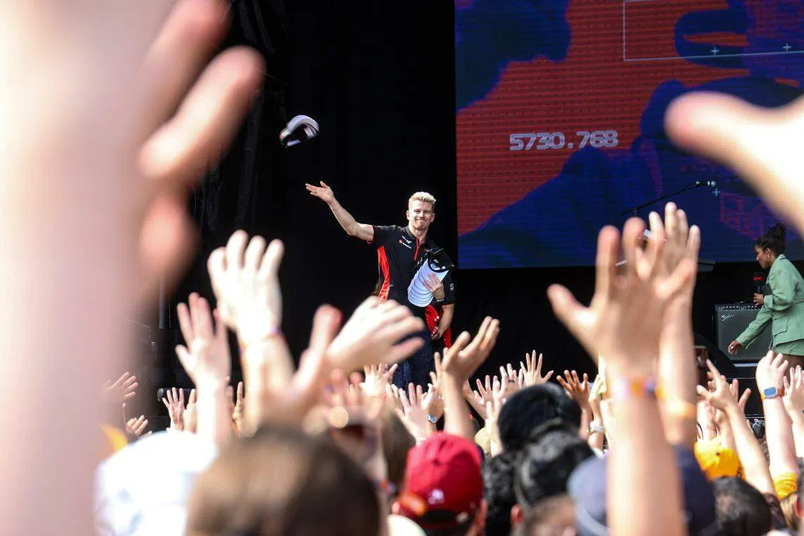 霍肯博格向车迷掷帽子，大家纷纷举手盼抢到礼物。（关俊威摄）