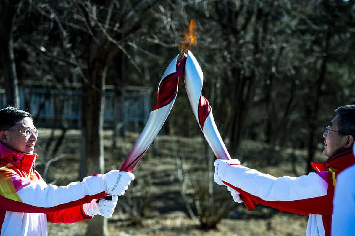 第105棒火炬手徐俊新（左）与第106棒火炬手齐腾云进行接力。（中新社）