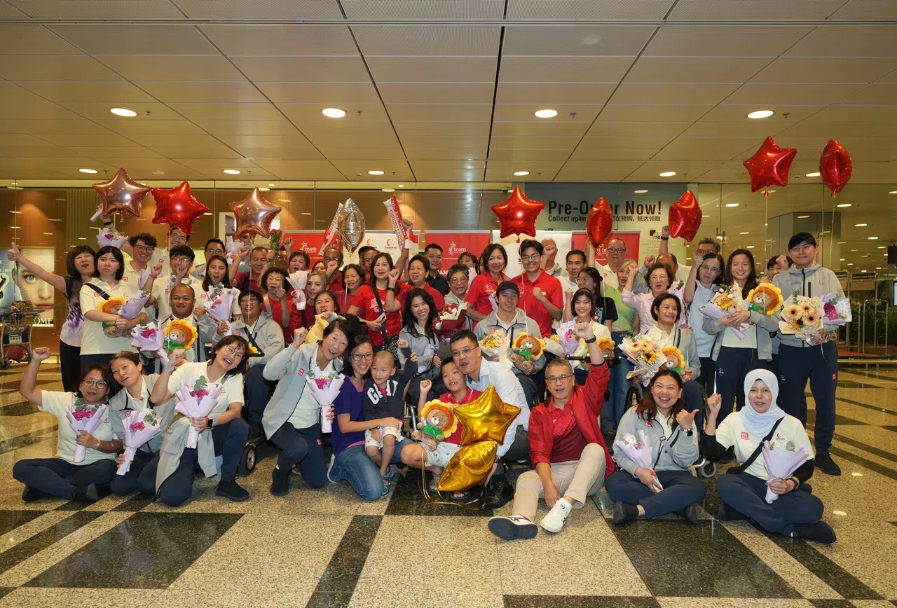 我国巴黎残奥会健儿从巴黎回来，家人和支持者到场迎接并和他们合照。前排右三为文化、社区及青年部长兼律政部第二部长唐振辉。（谢智扬摄）