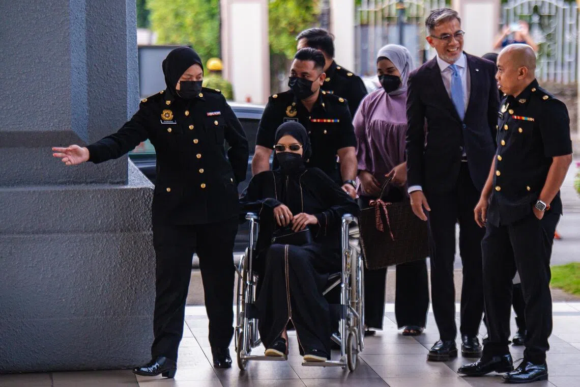 莫哈末哈菲祖丁的第三个妻子莎瓦妮（坐轮椅者）也在吉隆坡地庭被控四项受贿和洗钱罪。她因腿部不适，坐着轮椅出庭面控。（马新社）