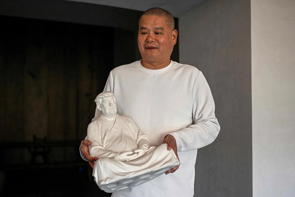 中国雕塑家洪金世在厦门的个人工作室内，捧着一座特朗普陶瓷佛像雕塑。图摄于去年12月9日。（法新社）