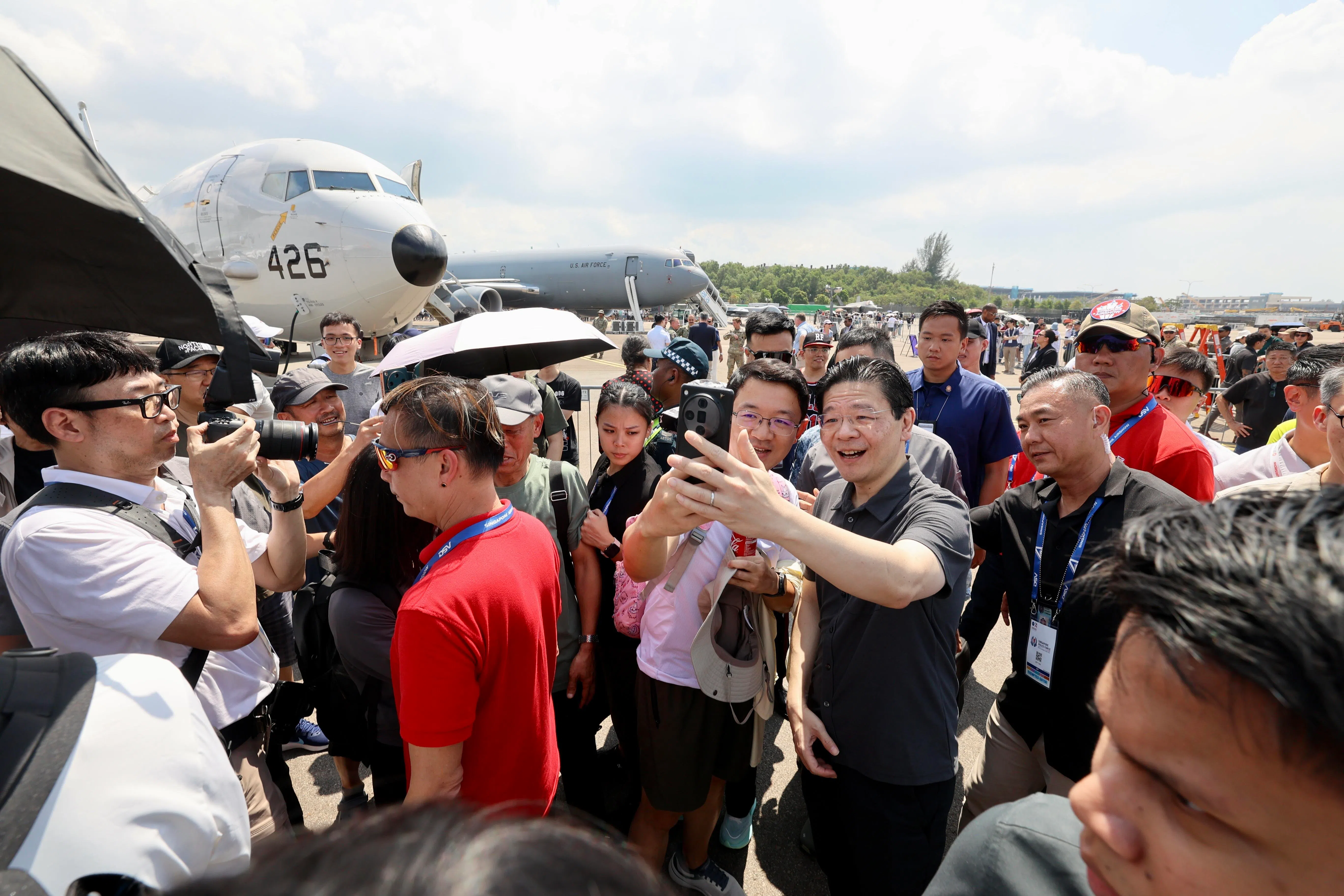 黄循财总理（右二，灰色短袖衬衫）星期六（2月7日）参观新加坡航空展，在户外静态展示区多次停下与公众合影。（邝启聪摄）