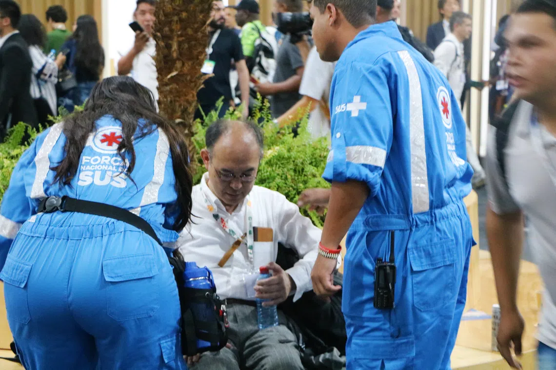 气候大会会场失火后，有人看似呼吸困难，坐在一旁的椅子，由急救人员照料。（蔡玮谦摄）