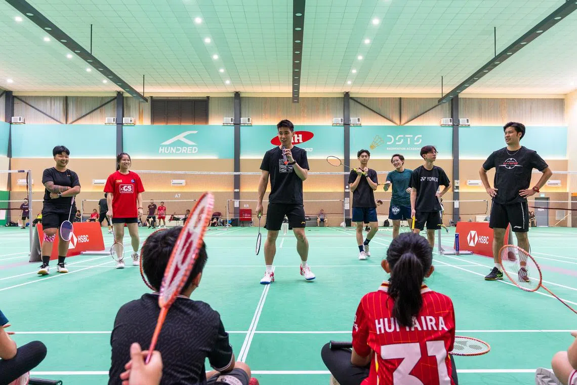 骆建佑（黑衣中）讲解羽毛球技巧，在旁的学生们听得津津有味。（汇丰新加坡提供）