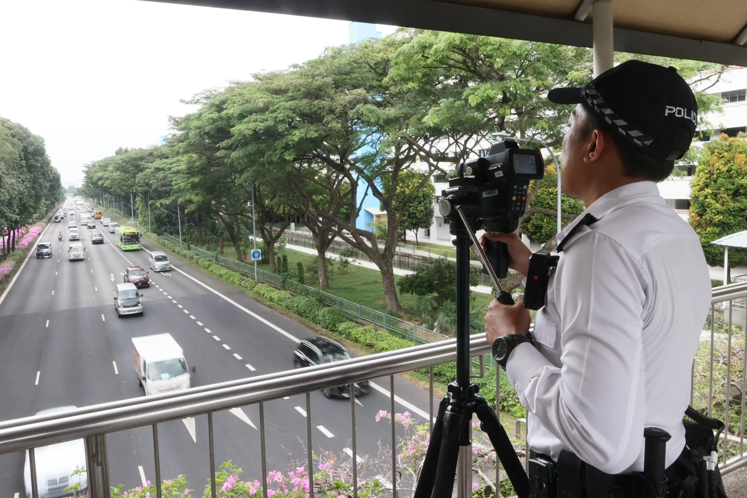 交警则站在天桥上将激光测速摄像机对准穿行的车辆，探测车辆的速度。（卓祾祎摄）