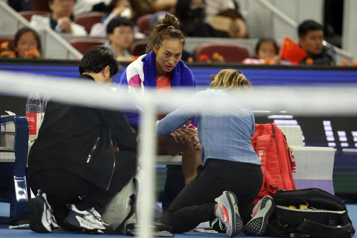 郑钦文比赛中手指受伤，在场边接受治疗。（路透社）