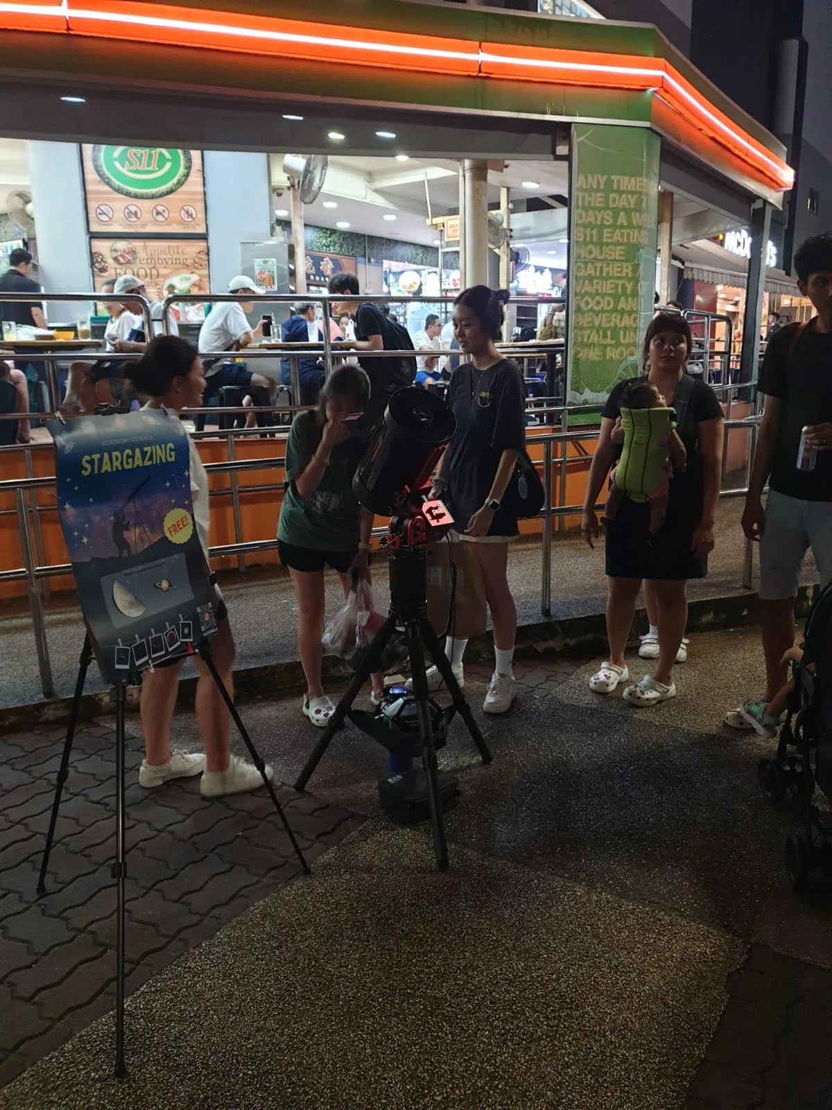 罗皓扬在宏茂桥架起望远镜，免费让路过的公众从望远镜观星赏月。他的目标是把这项活动带入不同社区。（受访者提供）