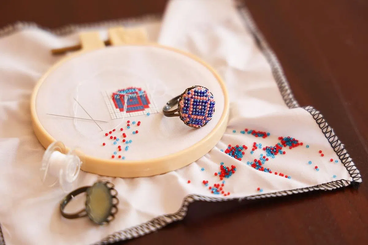 参加“早报文创空间”的读者在黄俊荣指导下，可自制一枚娘惹珠绣戒指。（蔡家增摄）