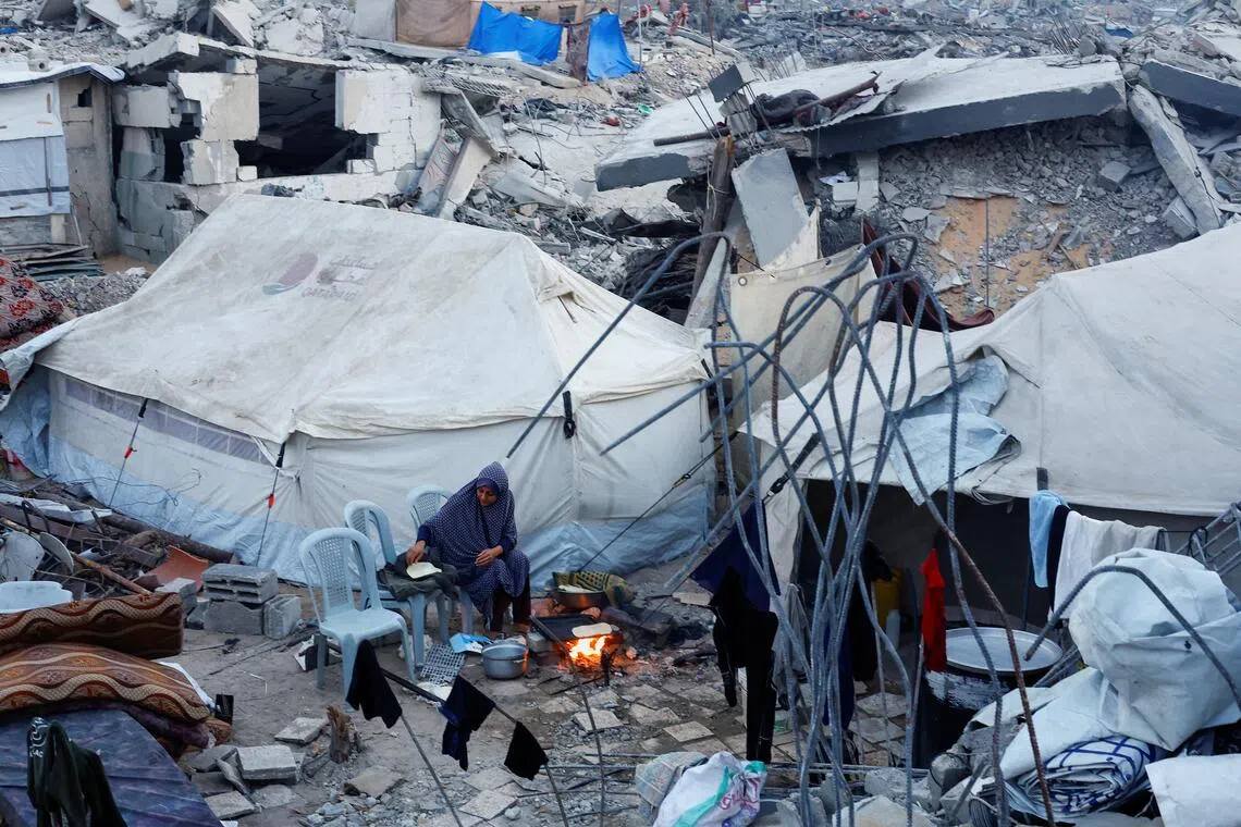 11月6日，加沙北部贾巴利亚的一名妇女在建筑物废墟旁准备食物。（路透社）