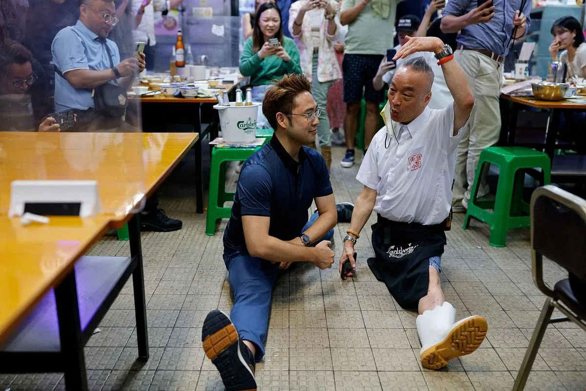 东宝小馆的最后一夜，经理“露比”（右，原名张醒超）表演一字马与食客合照。 （路透社）