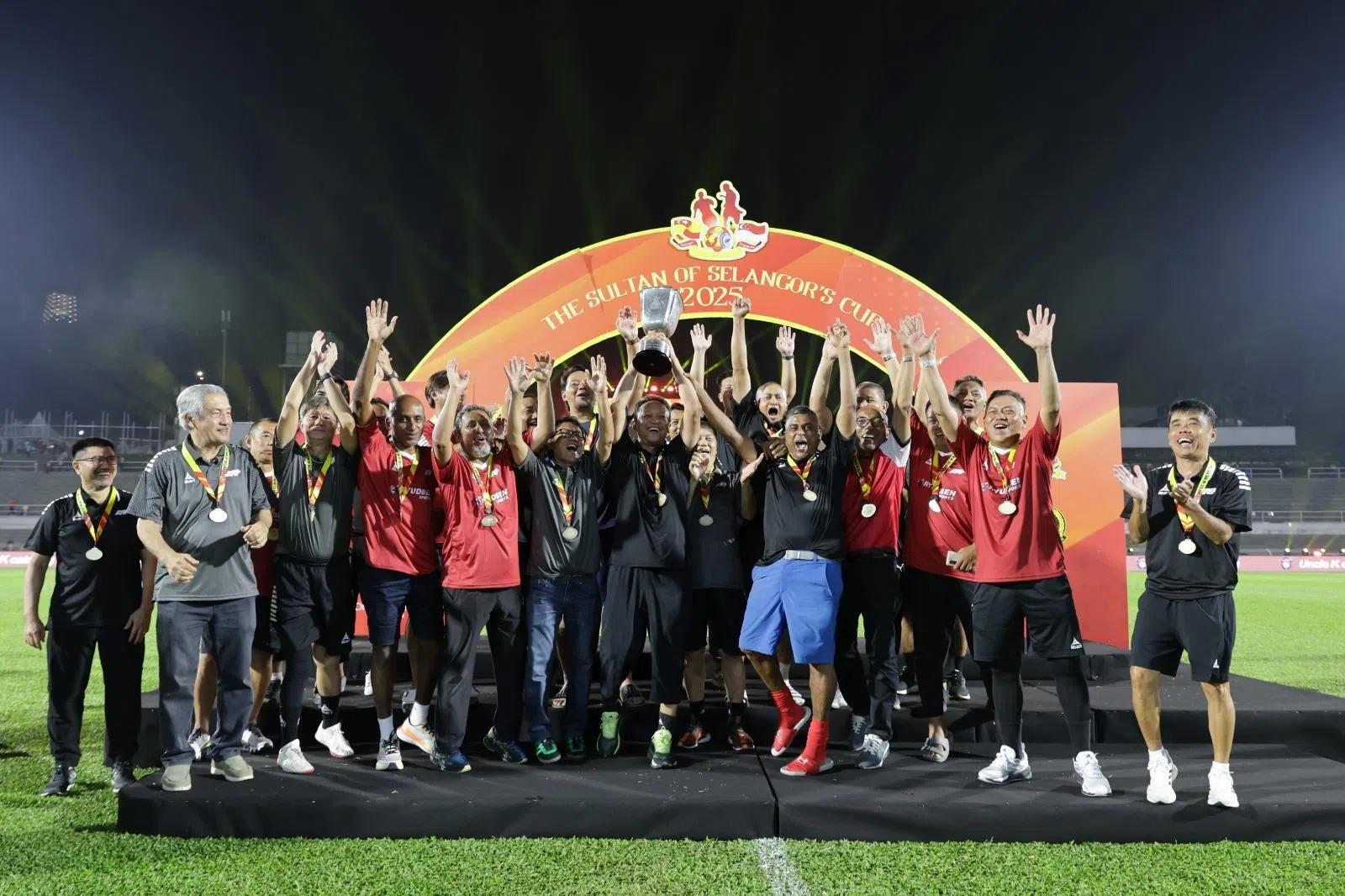 我国名宿队在比赛中发挥更佳，最后通过点球大战获胜，由范迪阿末（中）捧起奖杯。（新加坡足球总会提供）