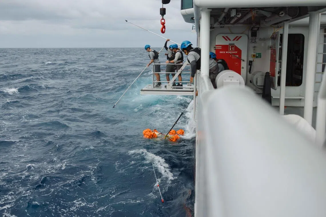 科研船海洋探索号人员从海里拉起在海底部署24小时的深海着陆器。（OceanX和新加坡国立大学提供）