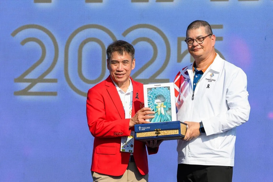 我国东运会代表团团长廖振兴（左）和泰国体育局副局长英伍德博士（右）交换礼品。（新加坡全国奥林匹克理事会提供）