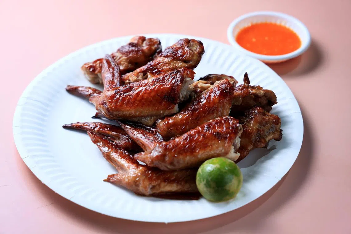 烤鸡翅皮脆肉香，搭配辣椒酱和酸柑汁，美味加倍。（龙国雄摄）