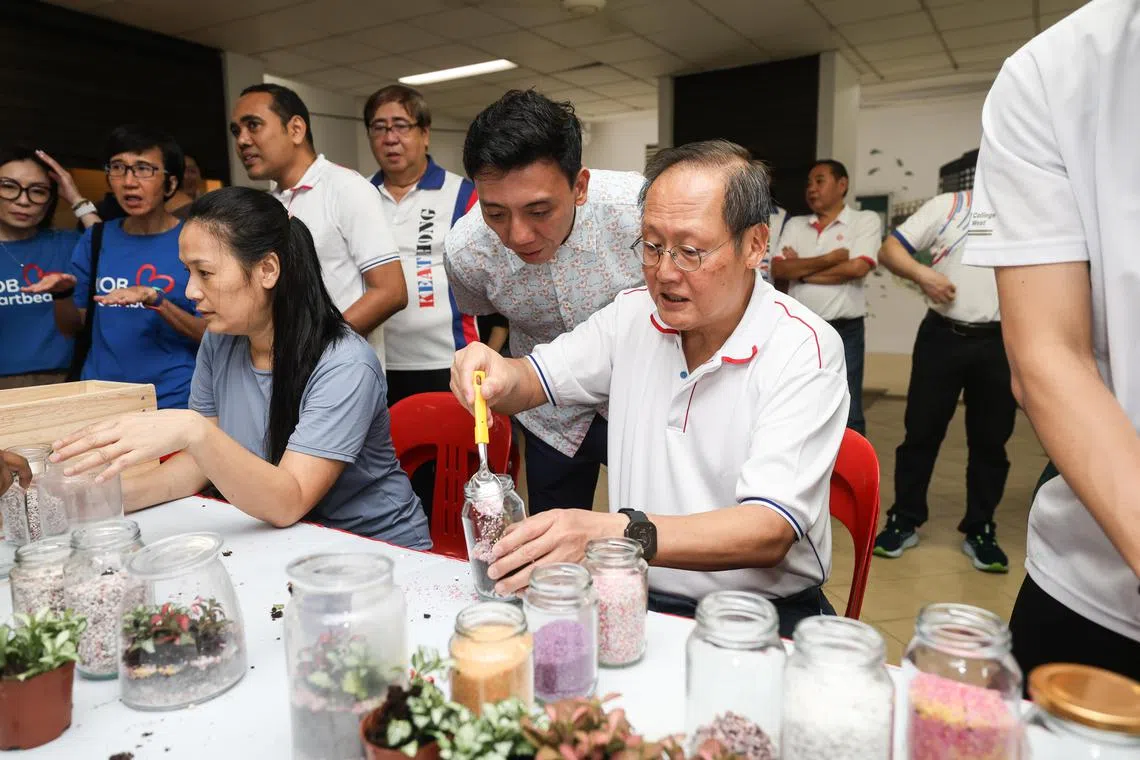 领军蔡厝港集选区的人力部长兼贸工部第二部长陈诗龙医生（右一）星期六出席社区活动，尝试利用玻璃瓶打造盆栽。其他蔡厝港集选区议员萧振祥（右二）和周凯年（右四）也在场。（关俊威摄）